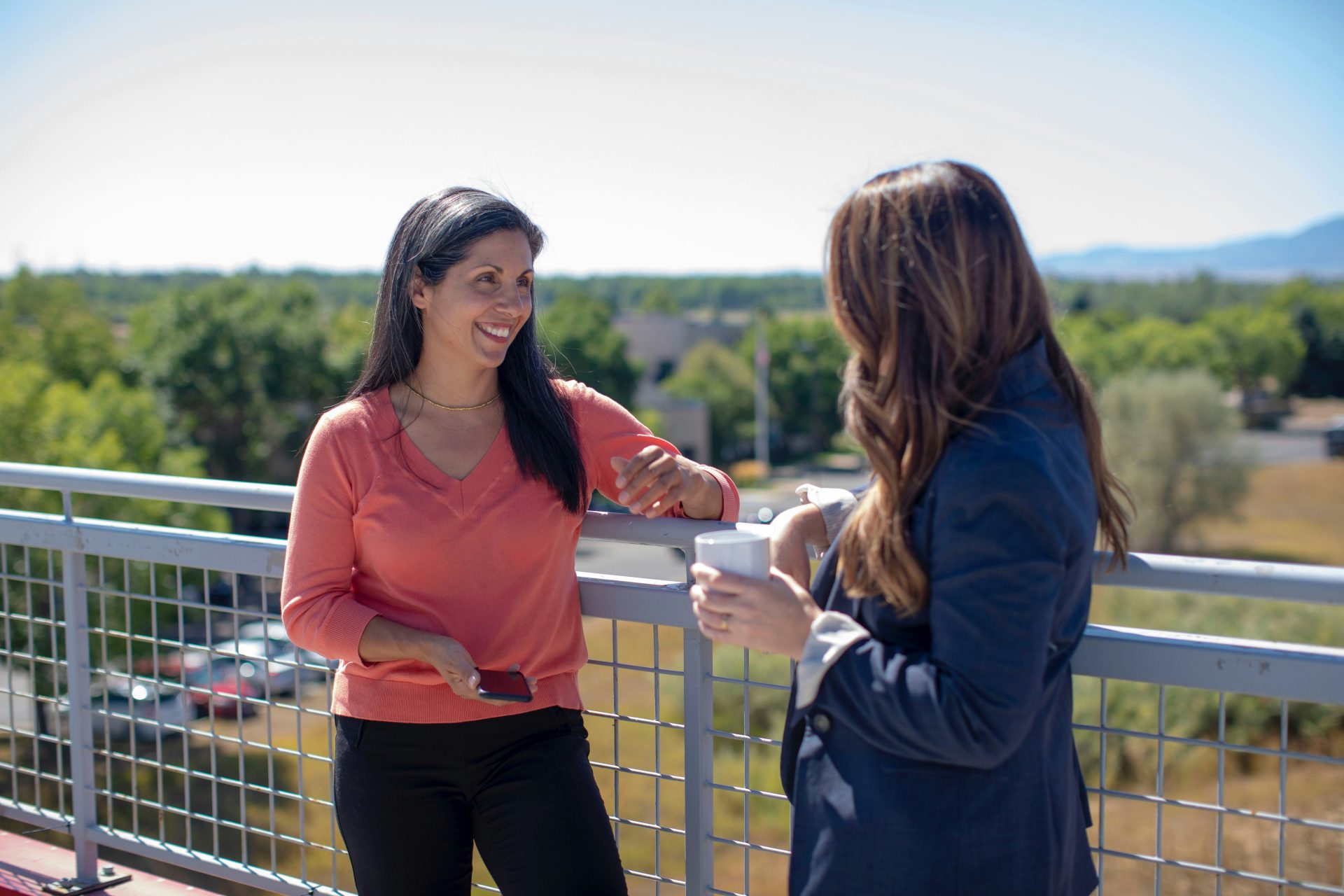 Two professional women chatting on a balcony
